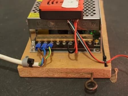 Das 5-V-Netzteil mit gekrimptem Kaltgerätekabel, montiert auf einer Holzplatte